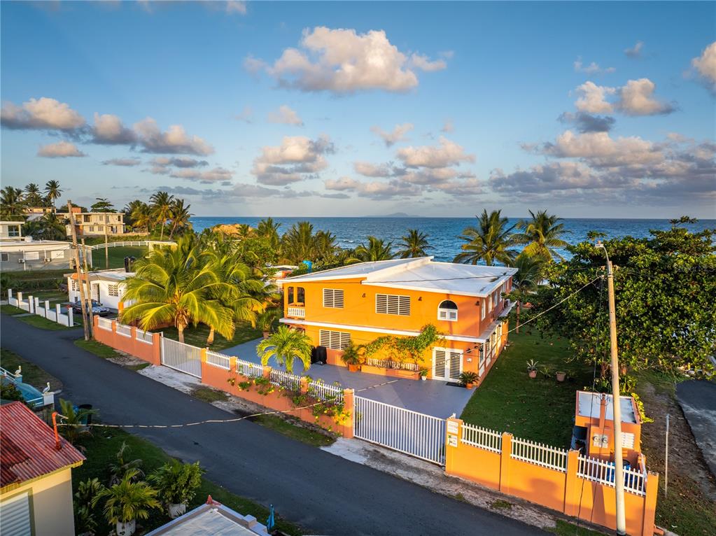 An aerial view shows an orange two-story house near the ocean with palm trees — Parcela #10 BARRIO CAMINO NUEVO, YABUCOA, PR