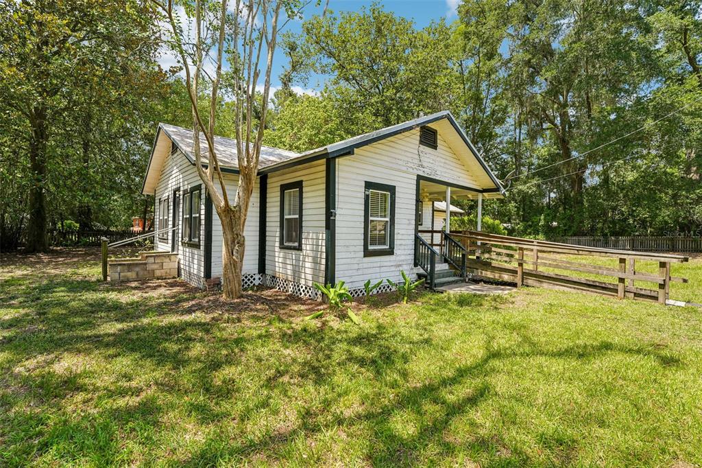 A white, single-story house with a wooden wheelchair ramp sits on a grassy lot — 14306 NW 145TH TERRACE, ALACHUA, FL