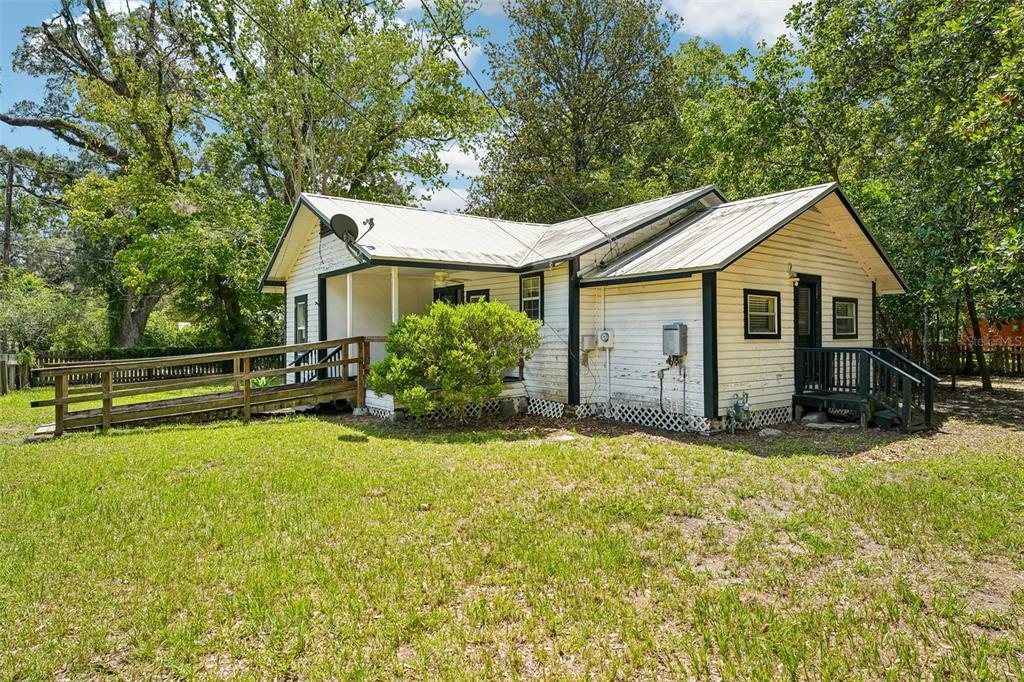 A white, single-story house with a metal roof, a wooden ramp, and a small porch — 14306 NW 145TH TERRACE, ALACHUA, FL