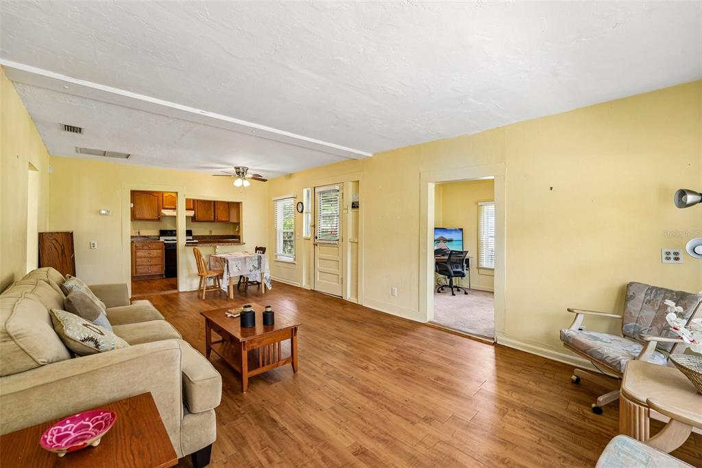 A living room with wood-look flooring, yellow walls, and an adjacent kitchen and office — 14306 NW 145TH TERRACE, ALACHUA, FL