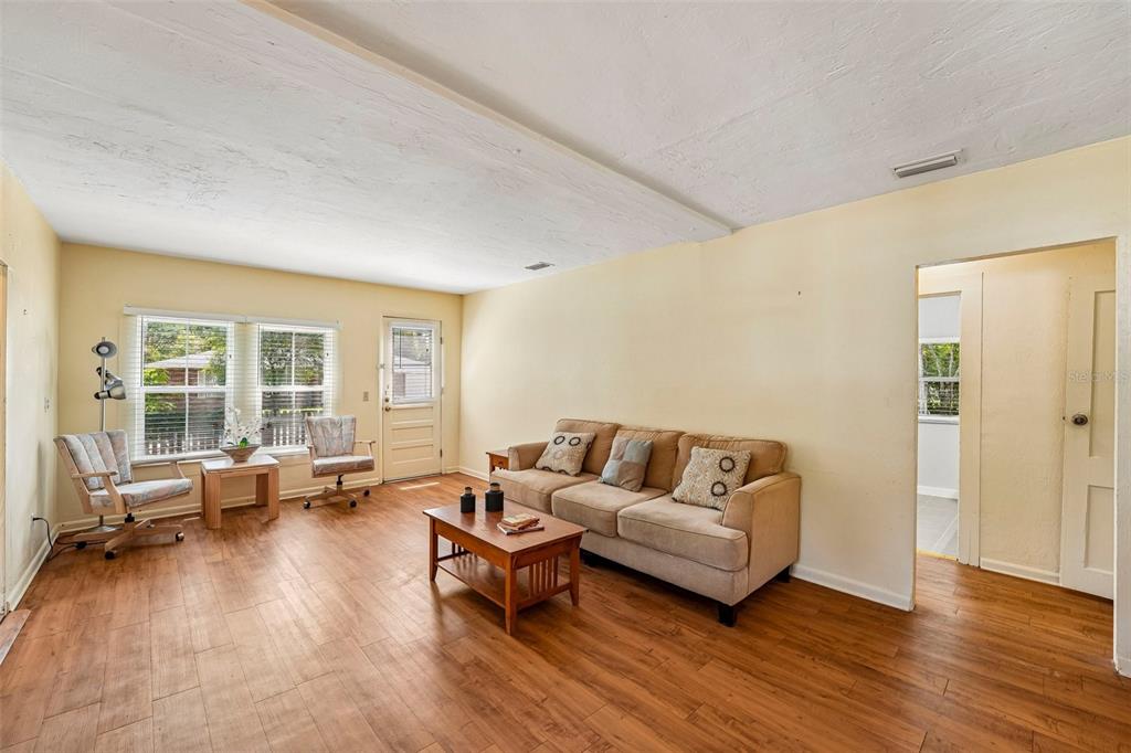 A living room features light yellow walls, wood-look flooring, a tan sofa, and two windows — 14306 NW 145TH TERRACE, ALACHUA, FL
