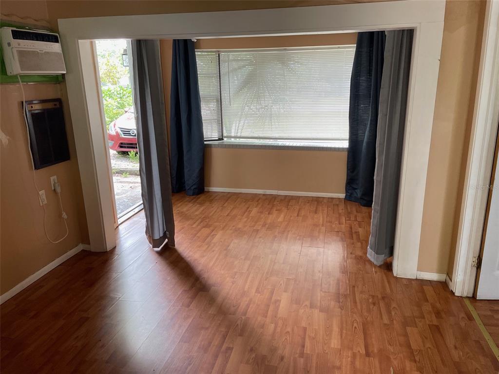 A room with wood-look flooring, a large window with blinds, and a doorway to outside — 1661 27TH AVENUE N, ST PETERSBURG, FL