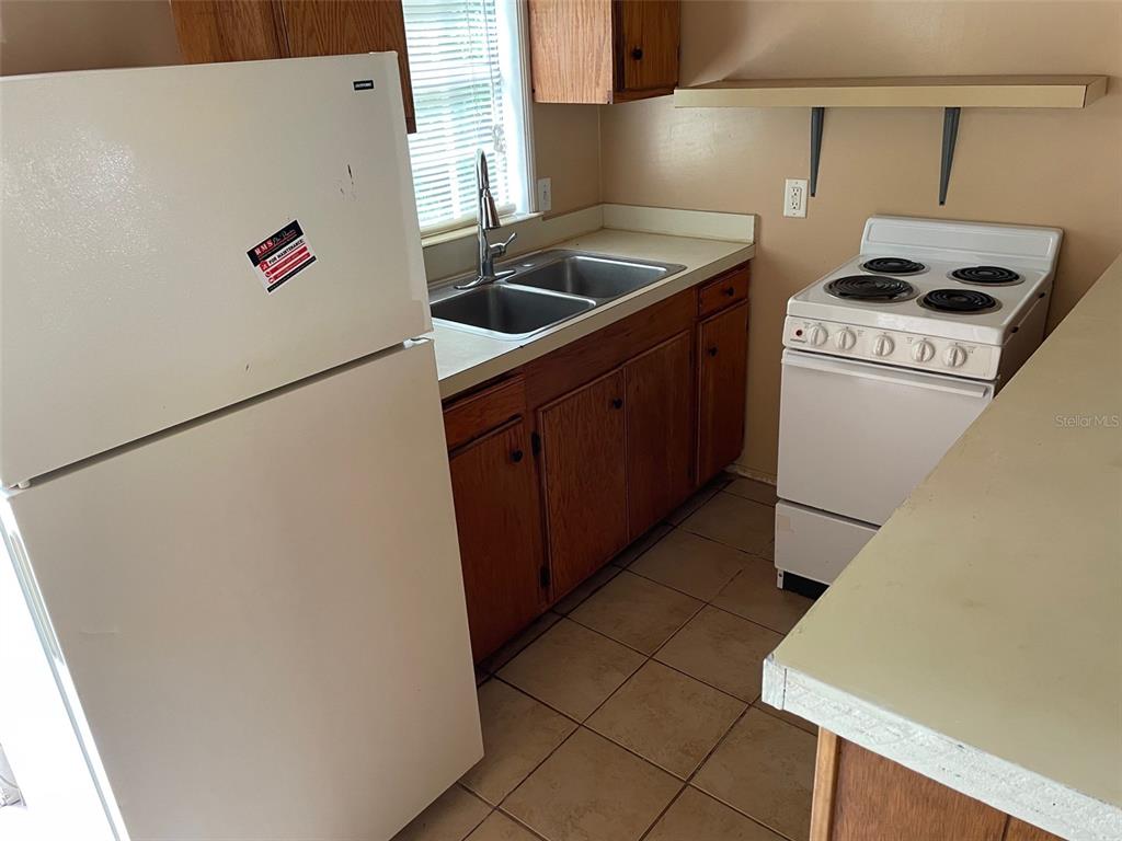 A kitchen features a white refrigerator, a double-basin sink, wooden cabinets, and a white stove — 1661 27TH AVENUE N, ST PETERSBURG, FL