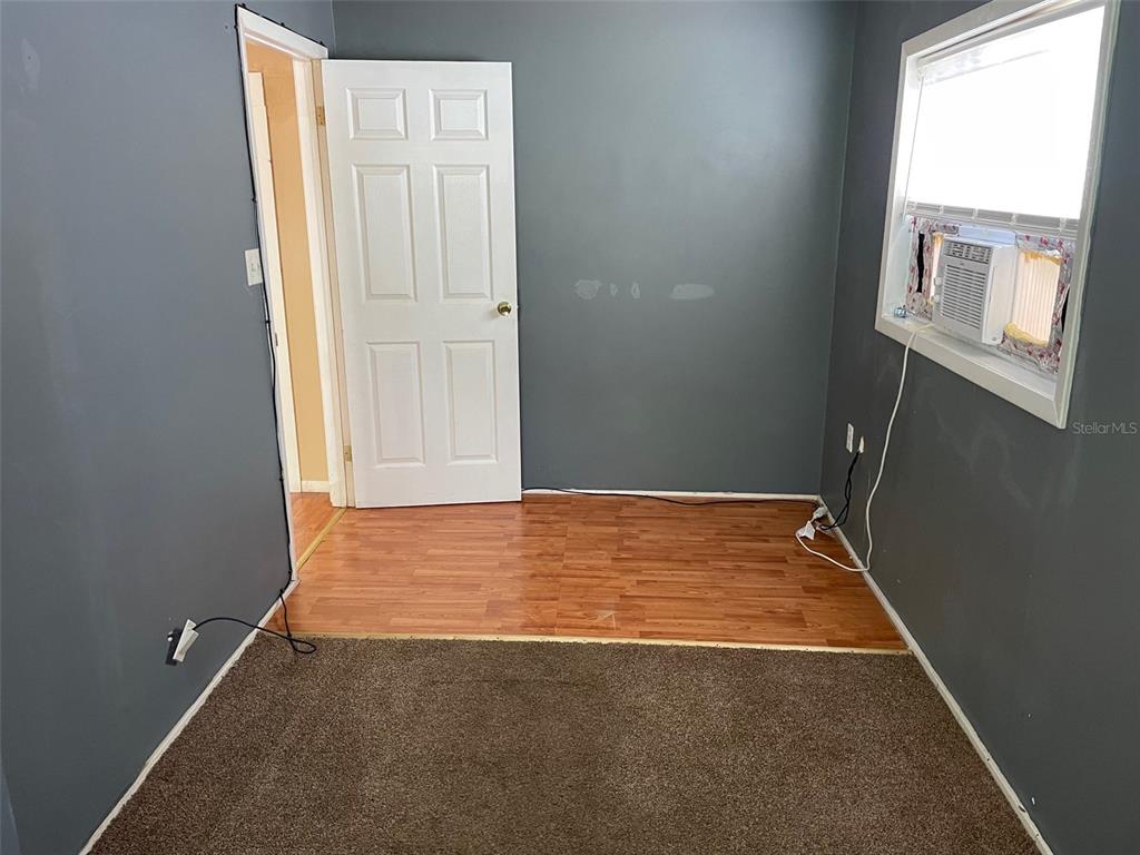 A room with gray walls, a brown carpeted area, and a wood-look laminate floor section — 1661 27TH AVENUE N, ST PETERSBURG, FL
