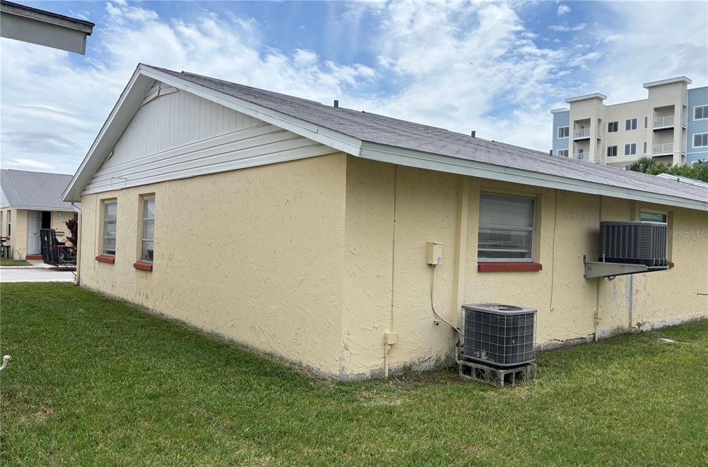 The exterior of a yellow, single-story building features a gabled roof and an air conditioner — 4923 GETNER STREET, NEW PORT RICHEY, FL