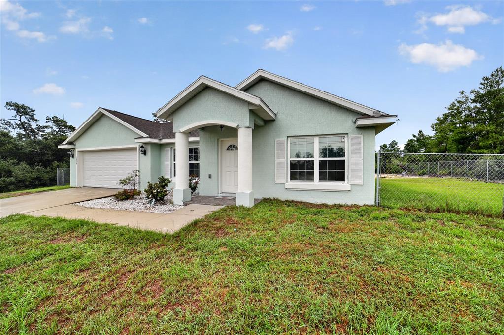 A light green single-story house with a two-car garage and a covered front porch — 3050 SW 177TH PLACE ROAD, OCALA, FL