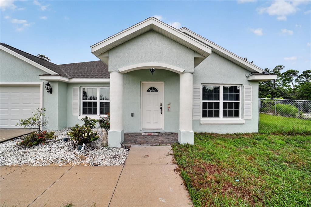 A light green single-story house features a white front door, two columns, and a garage — 3050 SW 177TH PLACE ROAD, OCALA, FL