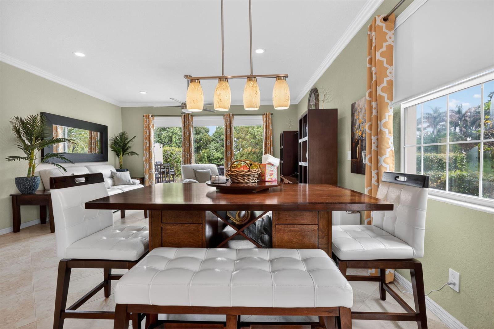 A dining area features a wooden table with white tufted chairs and a pendant light — 615 SW Glen Crest Way, Stuart FL 34997, STUART, FL