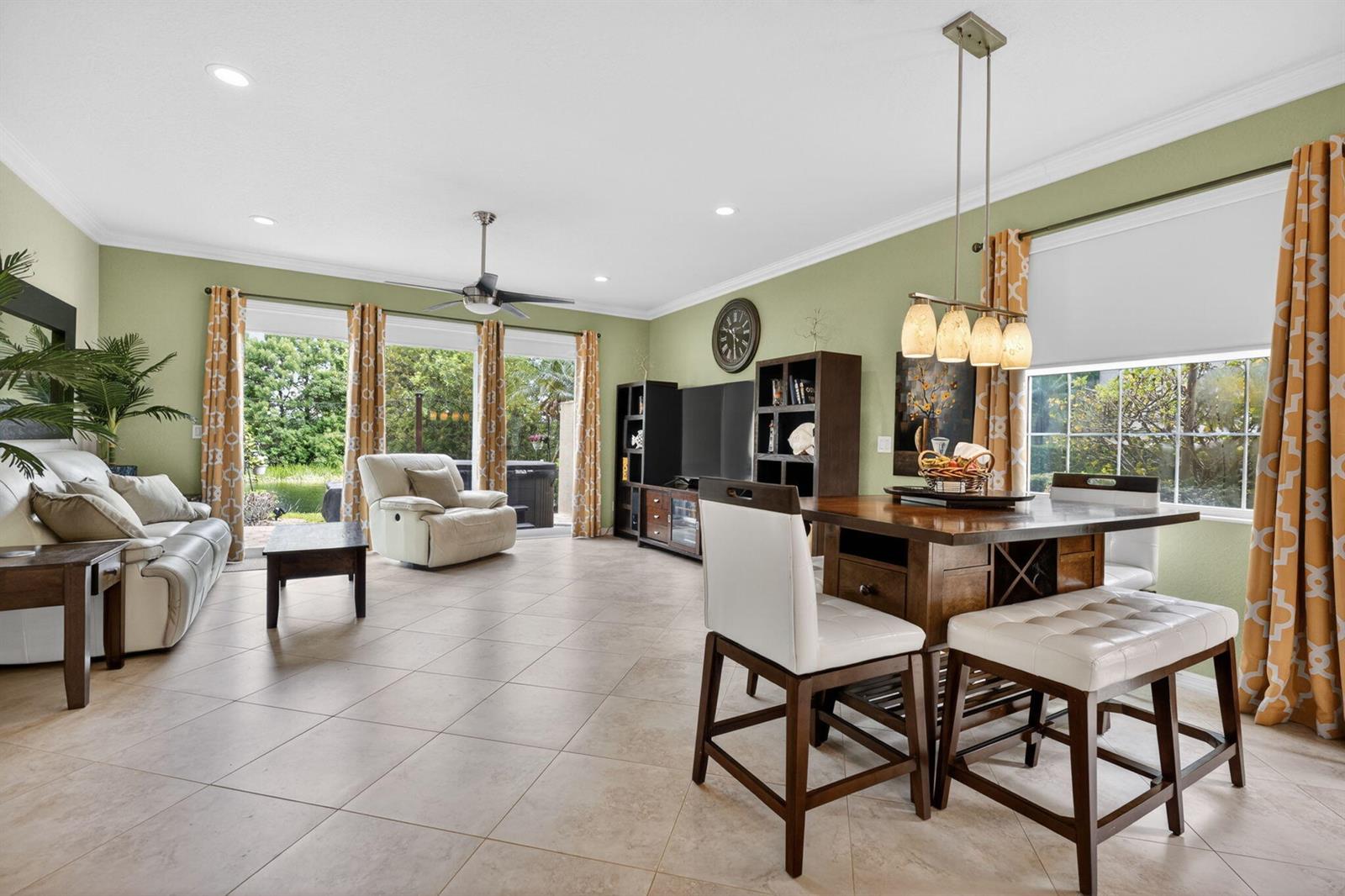 A living and dining area with light green walls, tile flooring, and sliding glass doors — 615 SW Glen Crest Way, Stuart FL 34997, STUART, FL
