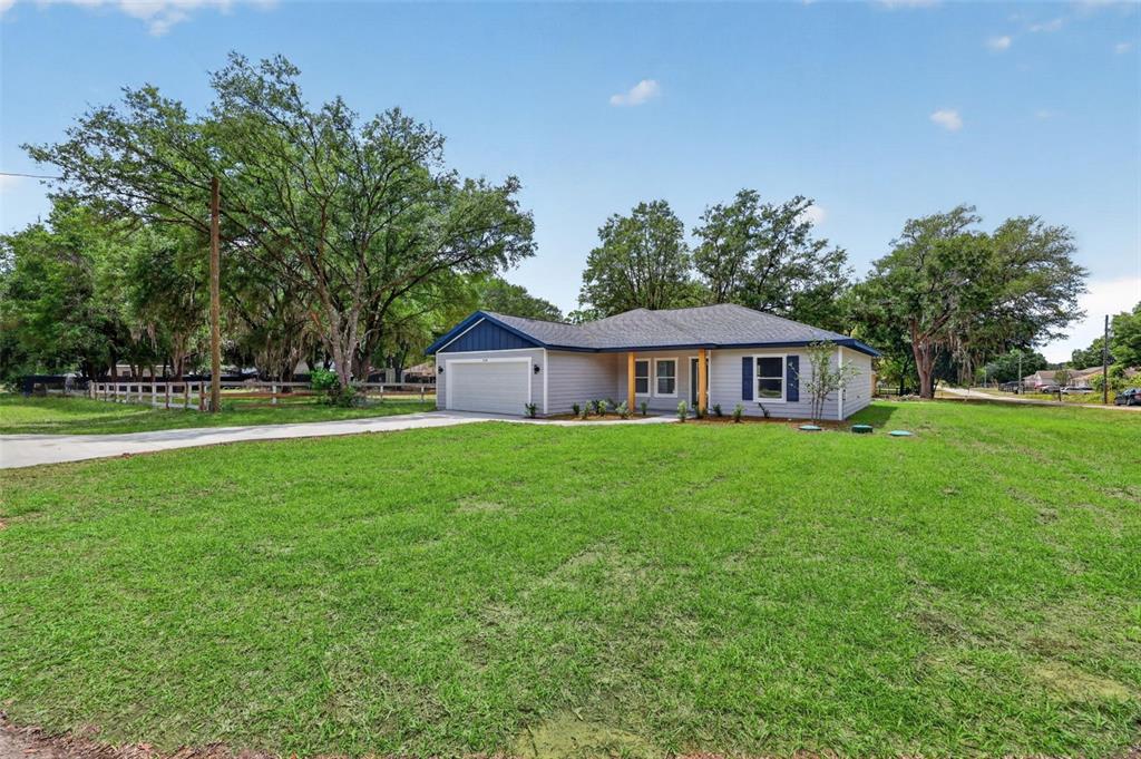 A single-story house with gray siding, a two-car garage, and a large front lawn — 10110 SW 135TH COURT, DUNNELLON, FL