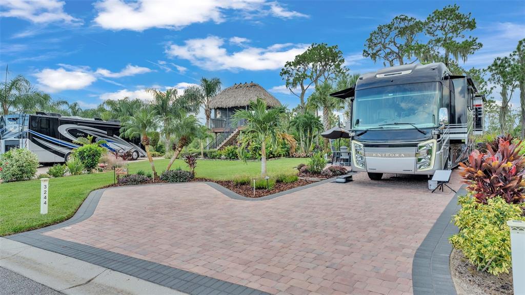 Two large motorhomes are parked on a paved driveway in front of a tiki hut — 3244 FISH HAWK DRIVE, POLK CITY, FL
