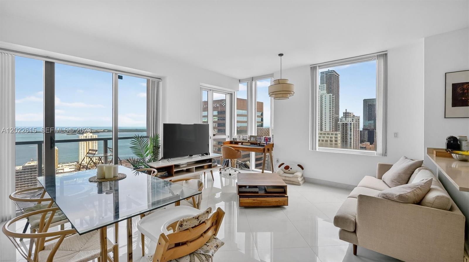 A modern living and dining area features floor-to-ceiling windows with city and water views — 500 Brickell Ave # 4102, Miami FL 33131, MIAMI, FL