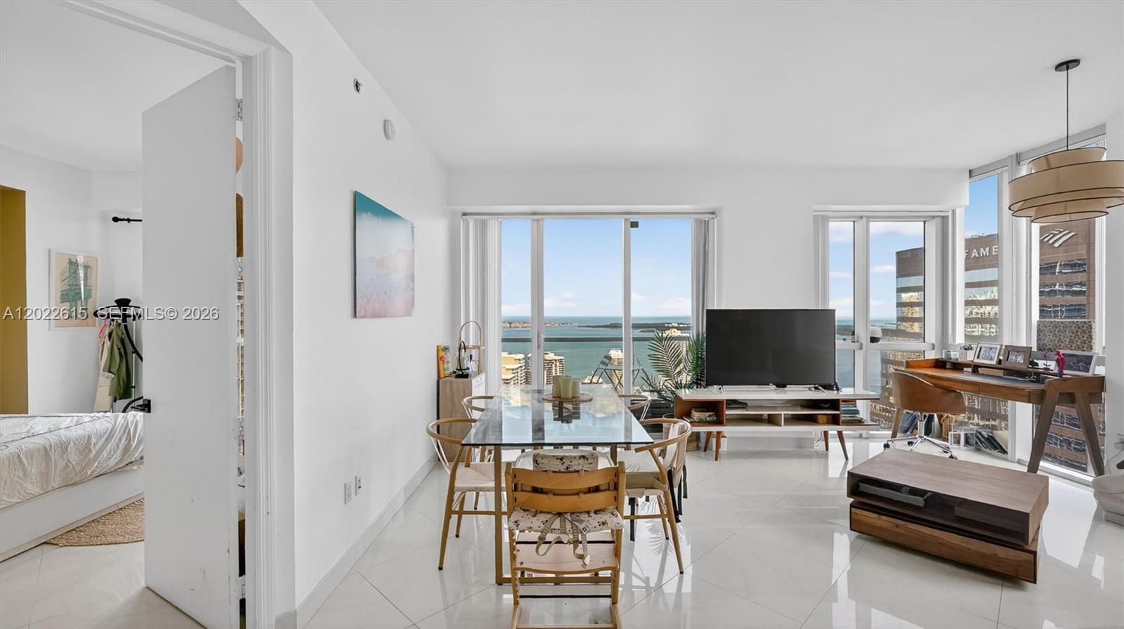 A bright living and dining area features white tile floors, floor-to-ceiling windows, and ocean views — 500 Brickell Ave # 4102, Miami FL 33131, MIAMI, FL