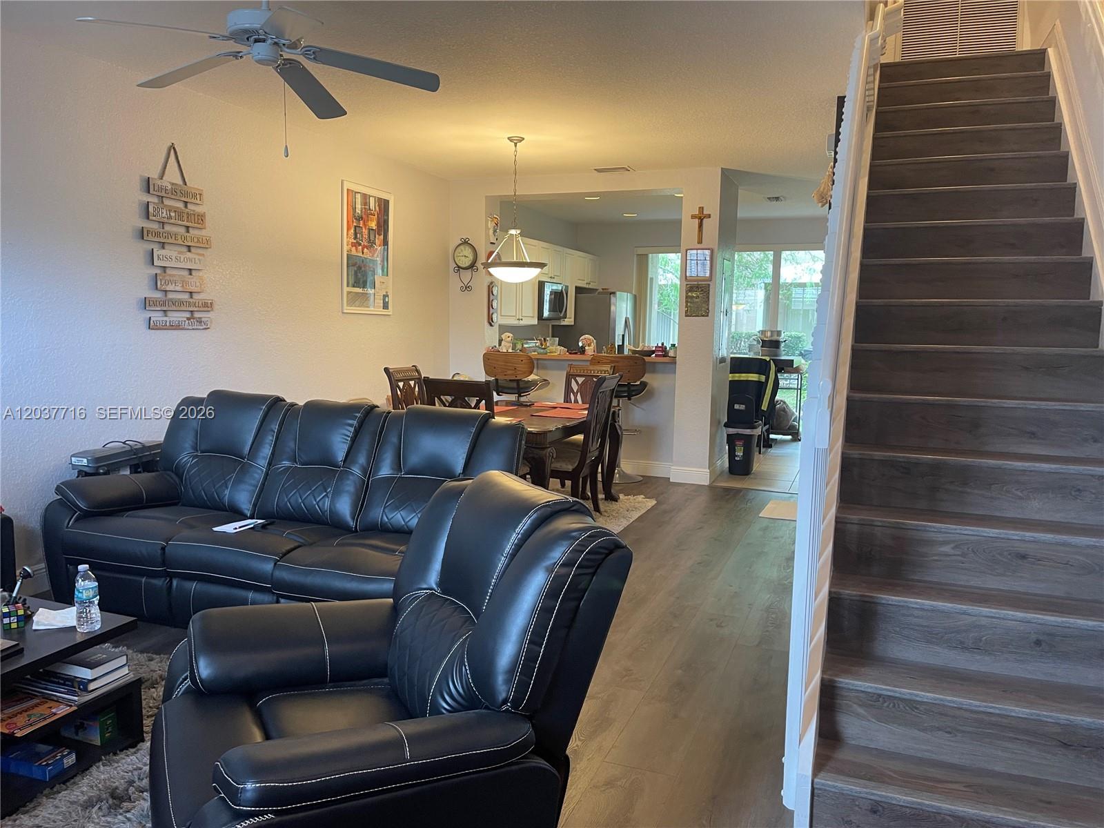 A living room with black leather furniture, wood-look flooring, and a staircase leading upstairs — 741 NW 42nd Ave, Plantation FL 33317, PLANTATION, FL