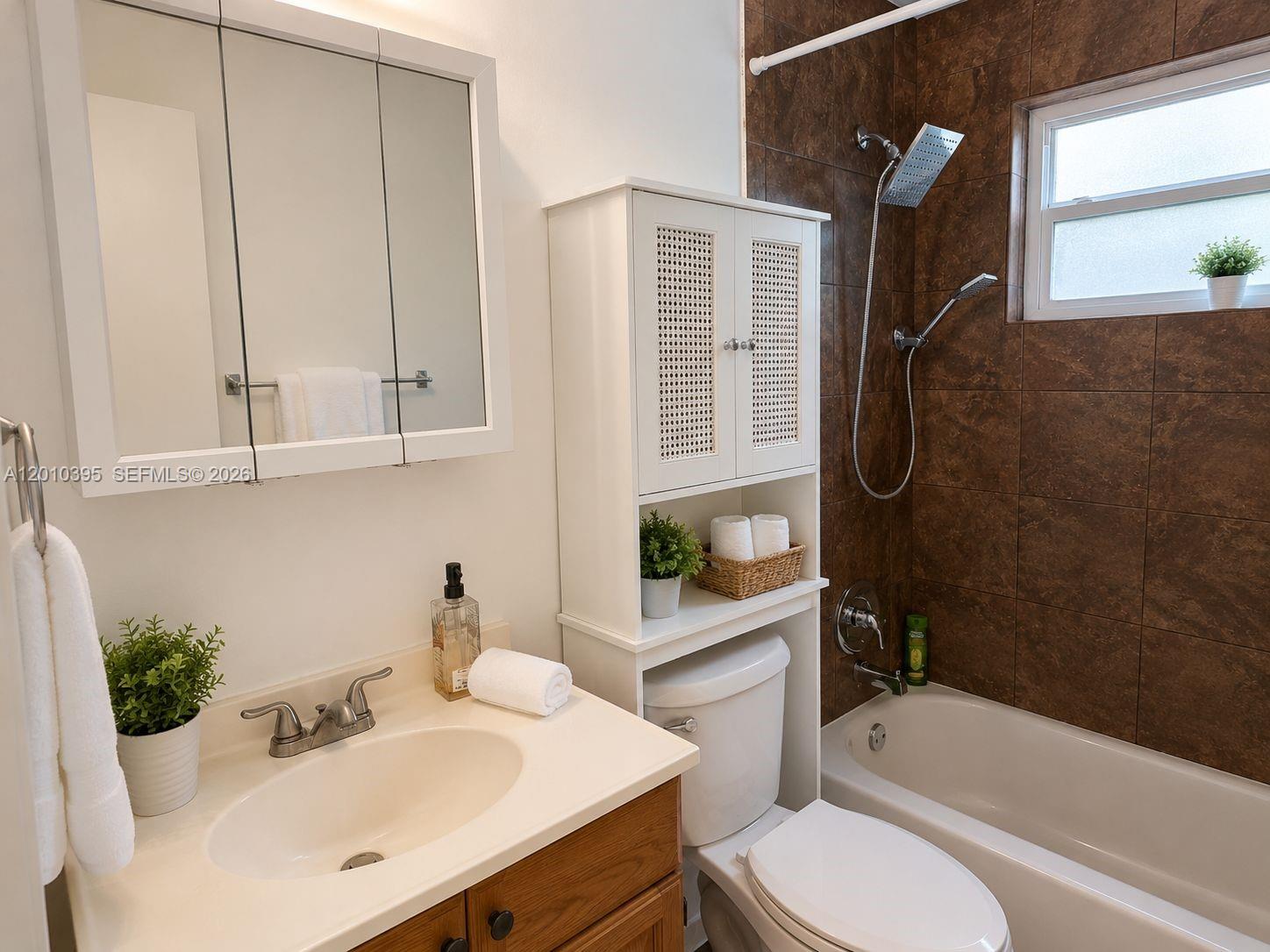 A bathroom features a vanity, a toilet with an over-the-toilet cabinet, and a tiled shower-tub — 2620 SW 51st St, Dania Beach FL 33312, DANIA BEACH, FL