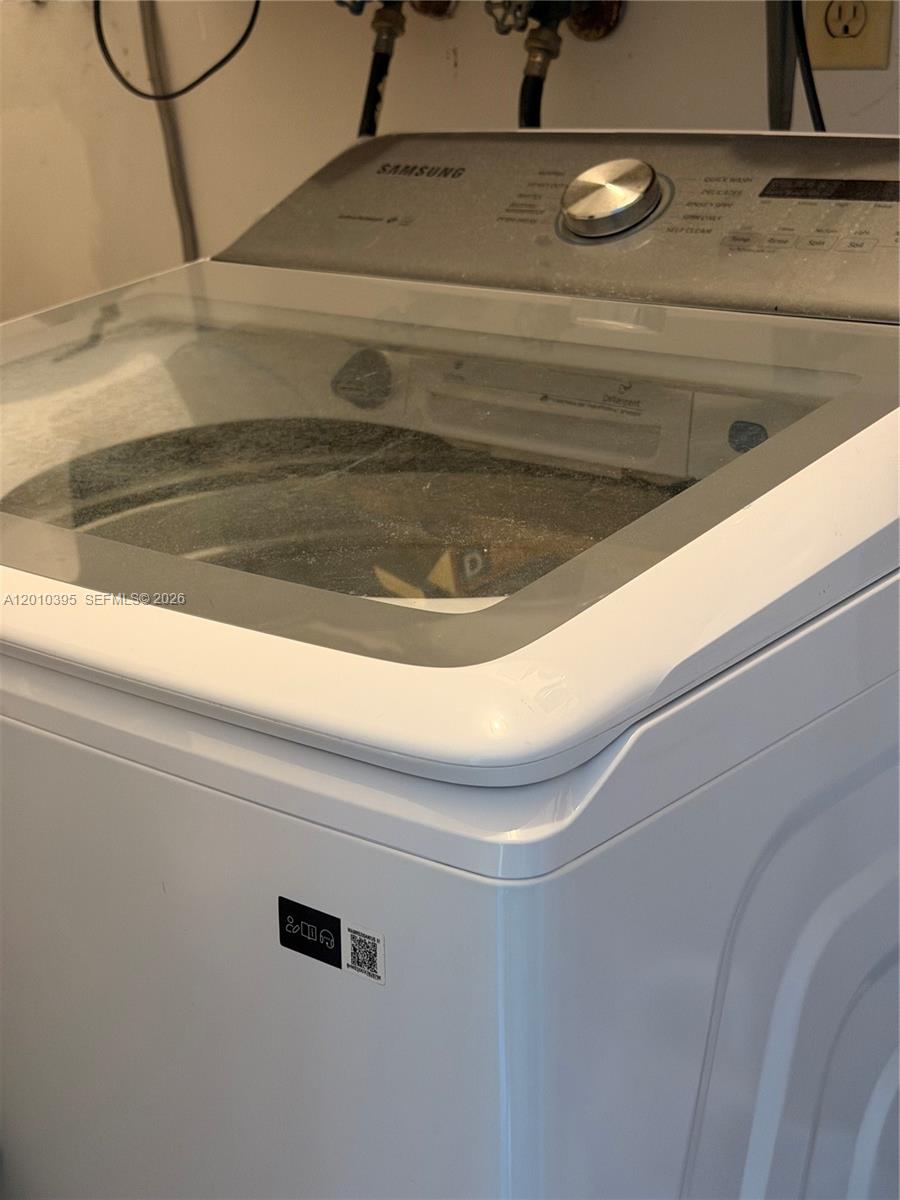 A white Samsung top-loading washing machine sits in a laundry area — 2620 SW 51st St, Dania Beach FL 33312, DANIA BEACH, FL