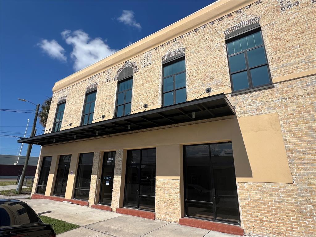 A two-story brick building with large windows and a black metal awning over the entrance — 2100 W MAIN STREET, TAMPA, FL