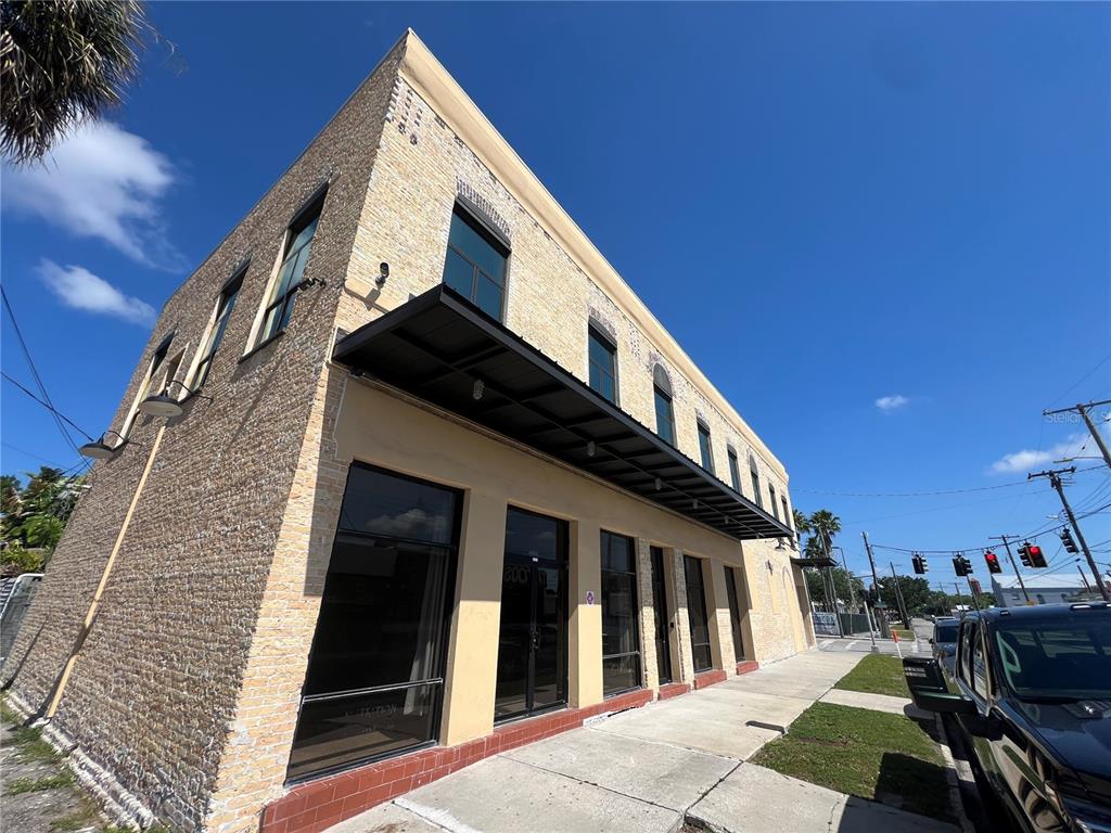 A two-story brick commercial building with large storefront windows and a black metal awning — 2100 W MAIN STREET, TAMPA, FL