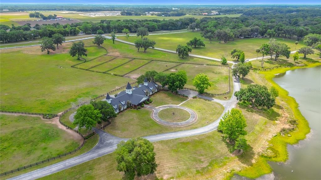 An aerial view shows a large house with a dark roof situated on a grassy estate — 6530 SE 156TH LOOP UNIT 3 & 4, SUMMERFIELD, FL