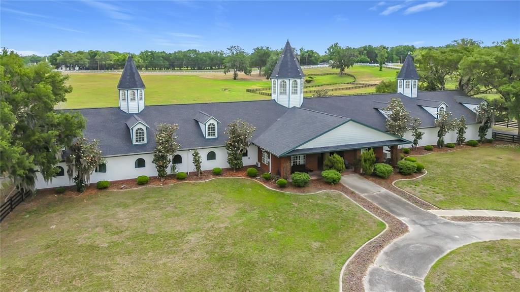 An aerial view of a long, white, multi-winged building with three turrets and dark roofing — 6530 SE 156TH LOOP UNIT 3 & 4, SUMMERFIELD, FL