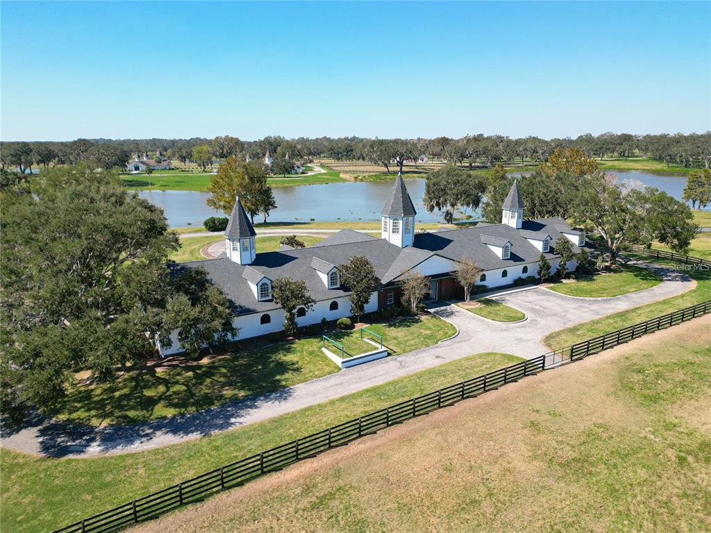 An aerial view of a white horse stable with three cupolas beside a lake — 6530 SE 156TH LOOP UNIT 3 & 4, SUMMERFIELD, FL