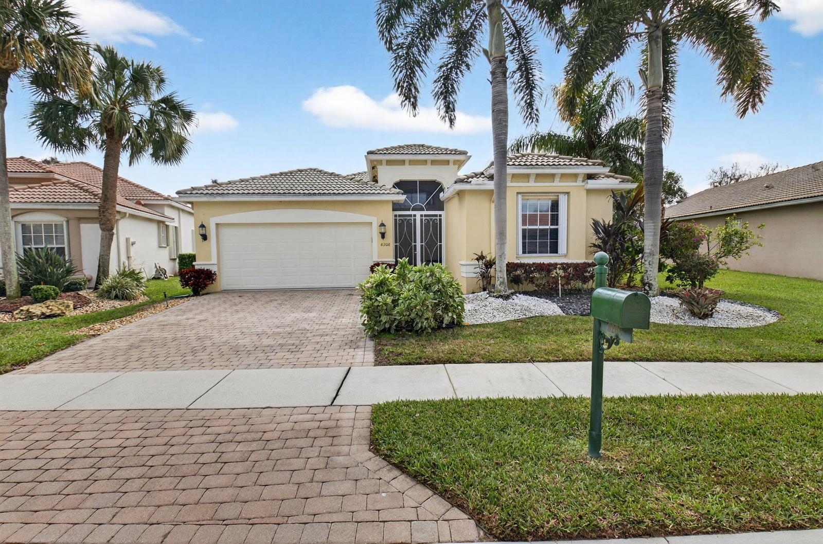 A single-story suburban house with a paved driveway, a two-car garage, and palm trees — 8208 Parini Way, Lake Worth FL 33467, LAKE WORTH, FL