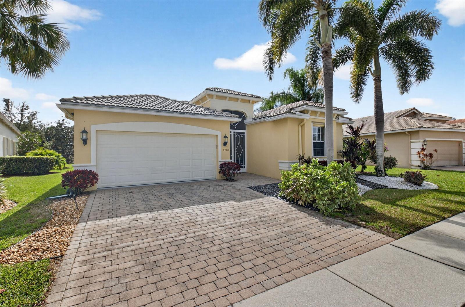 A single-story house with a paved driveway, palm trees, and a two-car garage — 8208 Parini Way, Lake Worth FL 33467, LAKE WORTH, FL