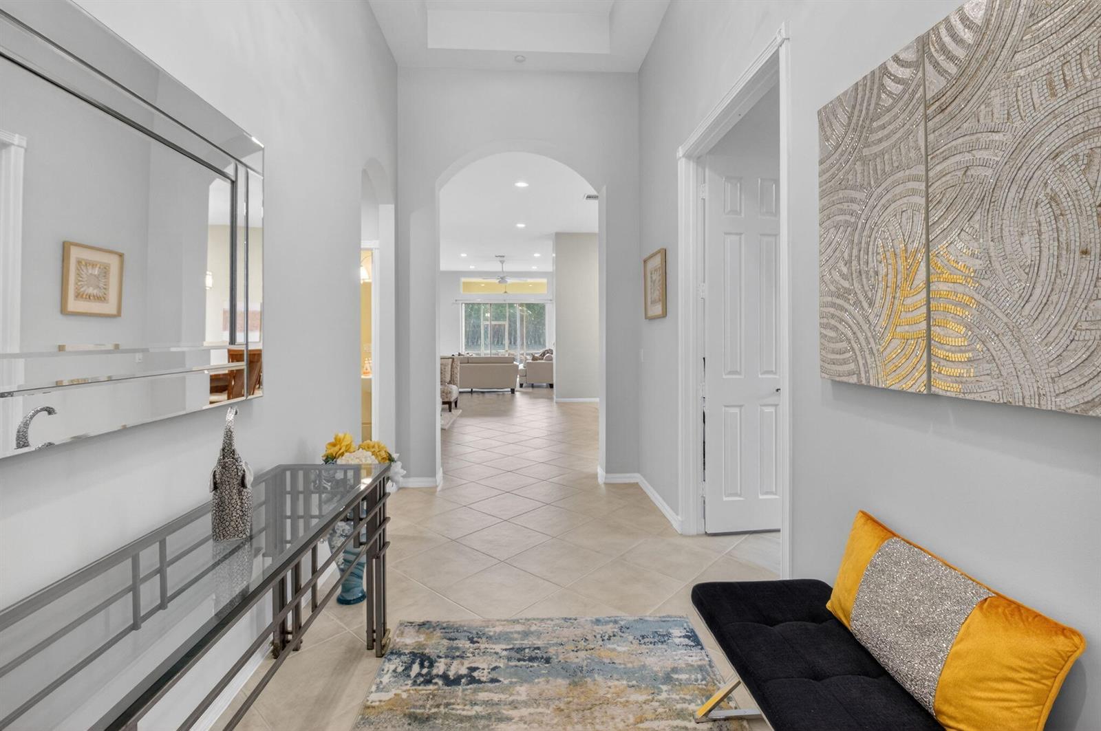 A bright foyer features tile flooring, a glass console table, and an arched entryway — 8208 Parini Way, Lake Worth FL 33467, LAKE WORTH, FL
