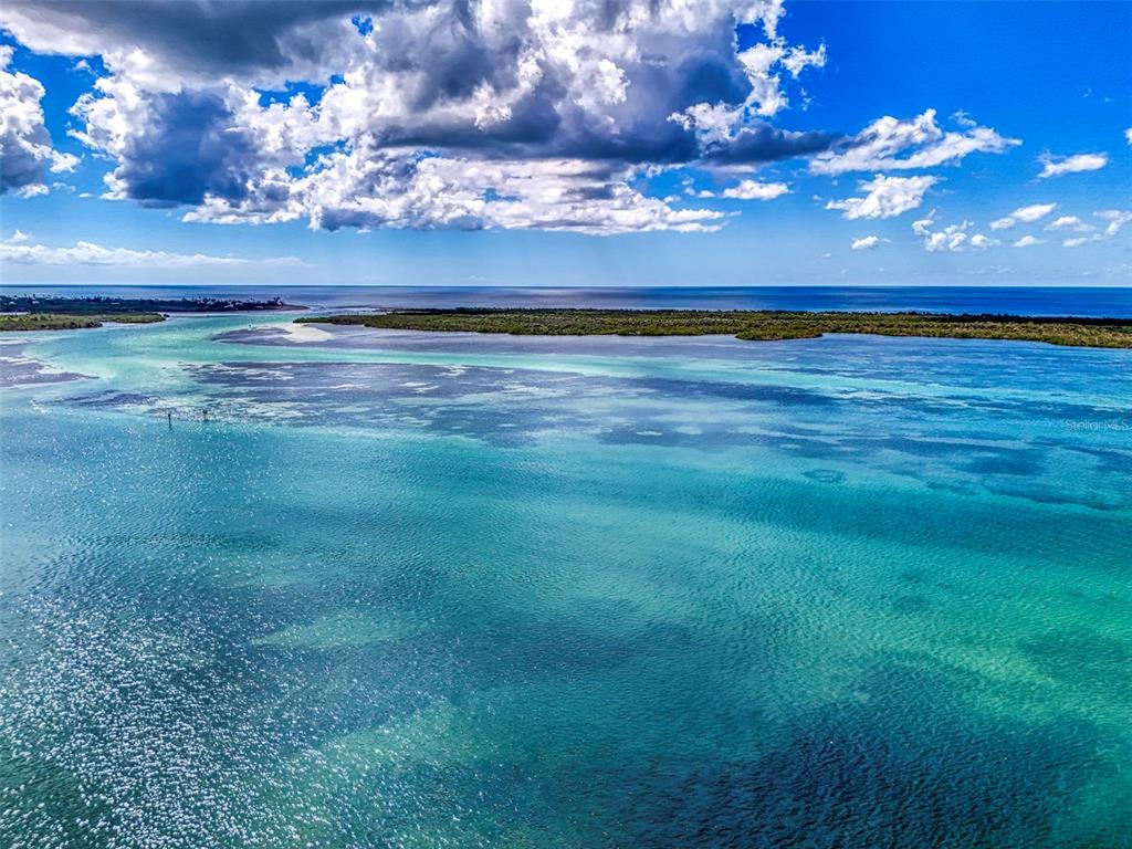 An aerial view shows a shallow turquoise bay with a long, narrow island in the distance — 1962 ARKANSAS AVENUE, ENGLEWOOD, FL