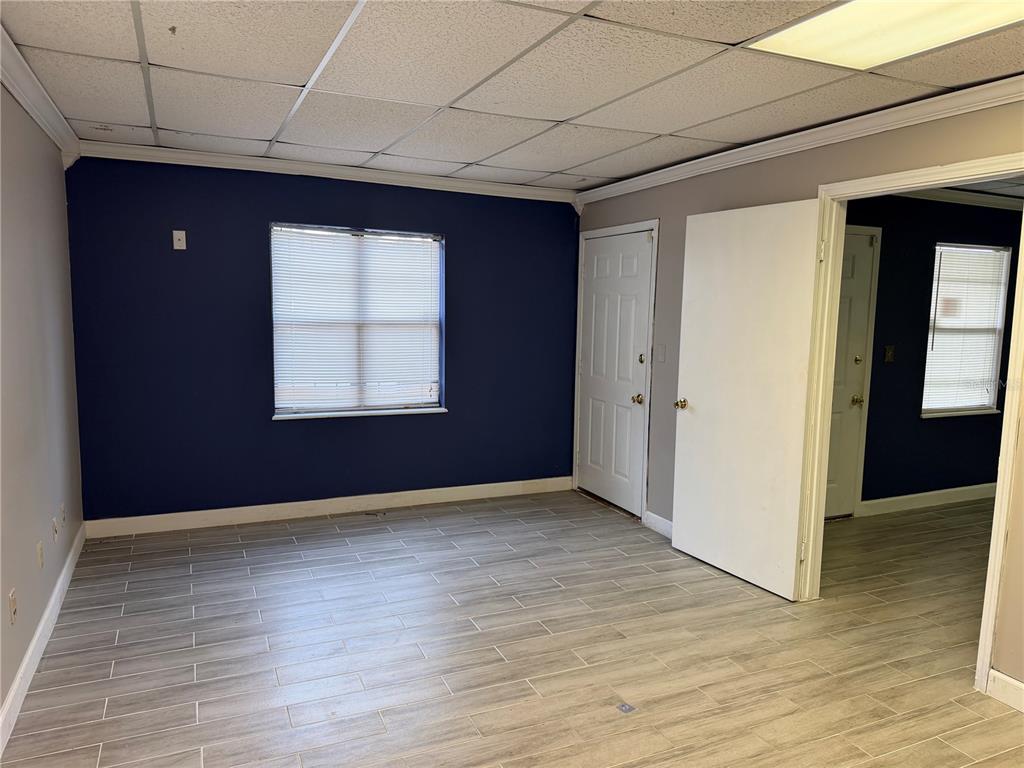 An empty room features gray wood-look tile flooring, a dark blue accent wall, and drop ceilings — 550 BALMORAL CIRCLE N UNIT 301/302, JACKSONVILLE, FL