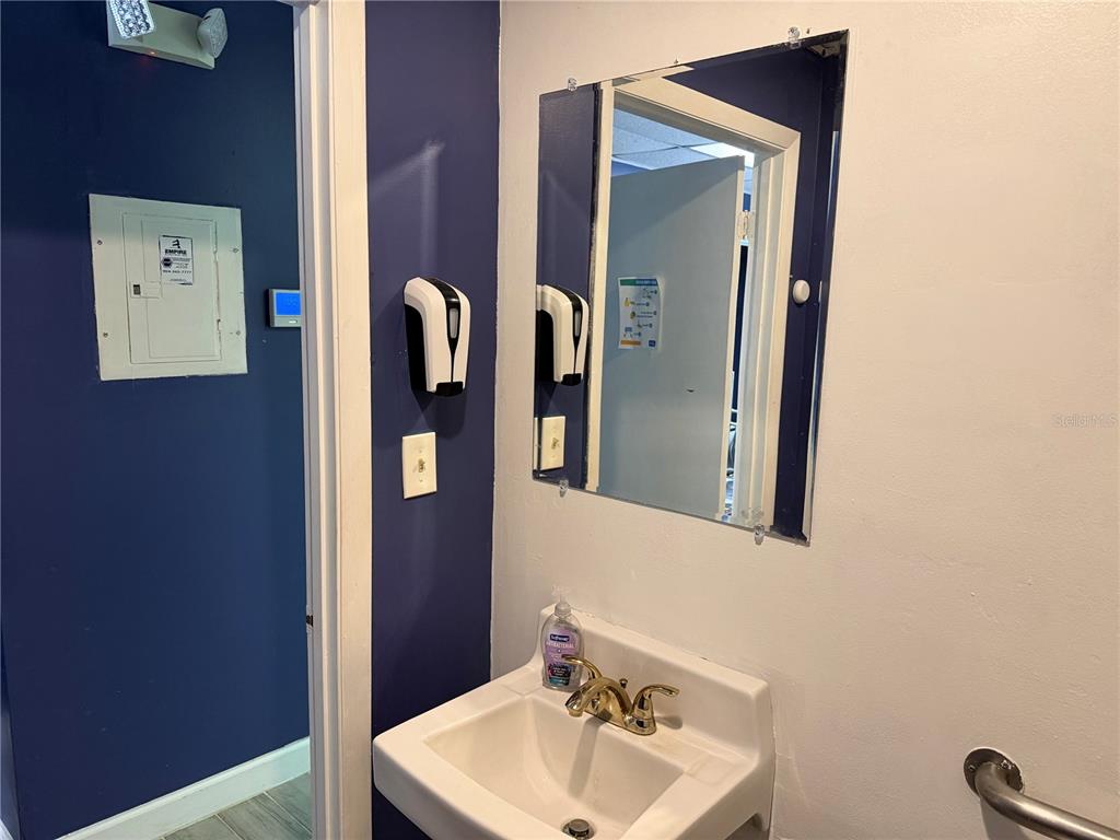 A bathroom features a wall-mounted sink, a mirror, and a dark blue accent wall — 550 BALMORAL CIRCLE N UNIT 301/302, JACKSONVILLE, FL