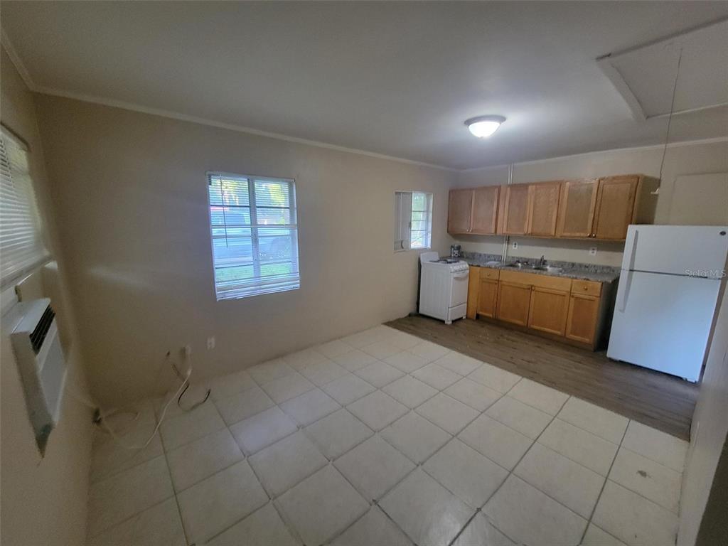 A kitchen and dining area features tiled floors, wooden cabinets, and white appliances — 729 E CAROLINA AVENUE, DELAND, FL