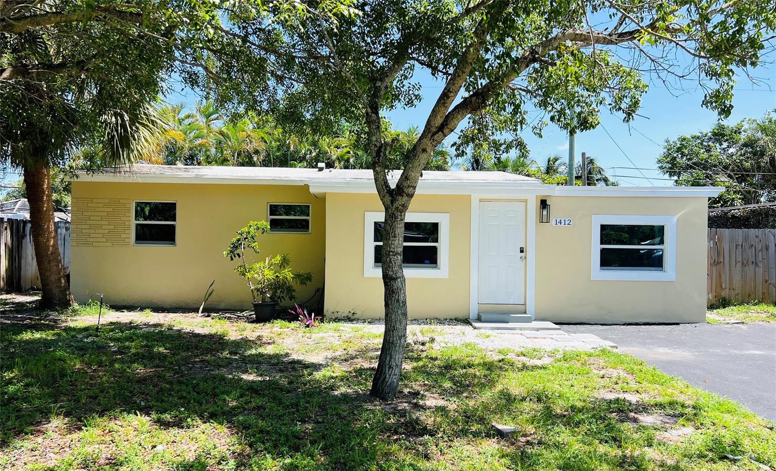 A single-story yellow house with a white front door and a paved driveway — 1412 NE 25th Court, Pompano Beach FL 33064, POMPANO BEACH, FL