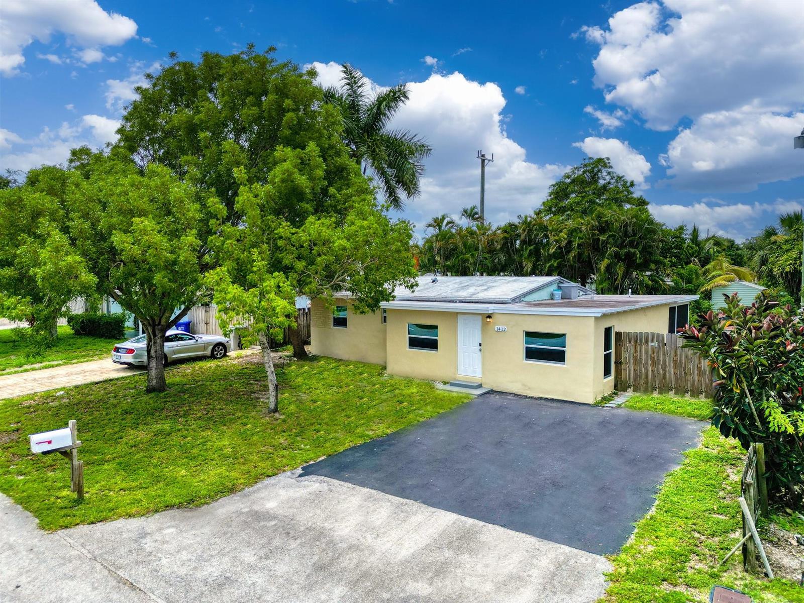 A single-story house with a yellow exterior, a paved driveway, and a large front yard — 1412 NE 25th Court, Pompano Beach FL 33064, POMPANO BEACH, FL