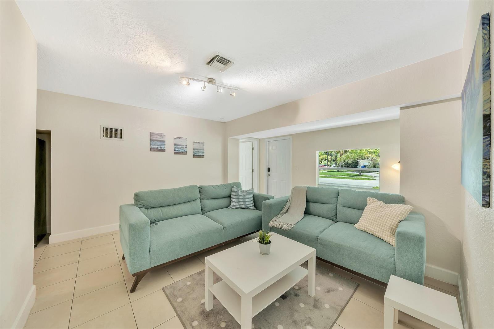A living room features two light blue sofas, a white coffee table, and tile flooring — 1412 NE 25th Court, Pompano Beach FL 33064, POMPANO BEACH, FL