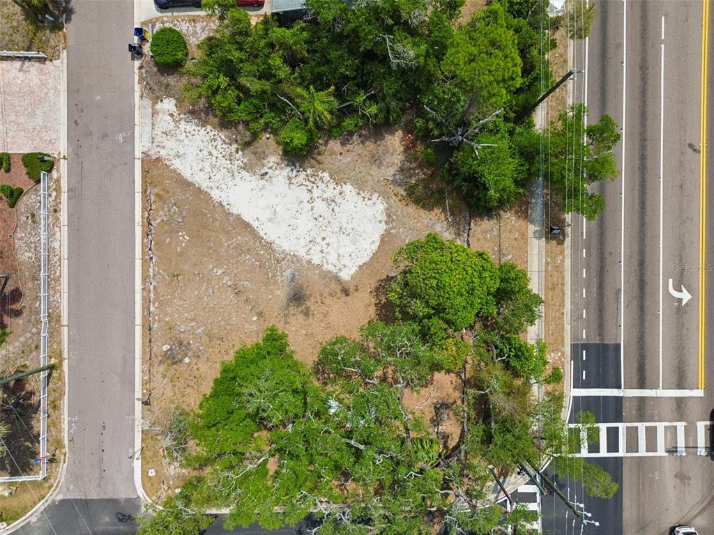 An aerial view shows a vacant, partially wooded lot situated between a road and street — 1107 BROWNELL STREET, CLEARWATER, FL