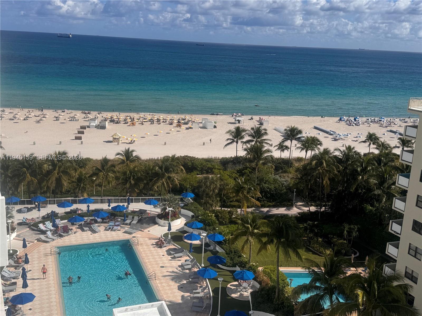 An elevated view of a swimming pool, palm trees, and a beach along the ocean — 100 Lincoln Rd # 1230, Miami Beach FL 33139, MIAMI BEACH, FL