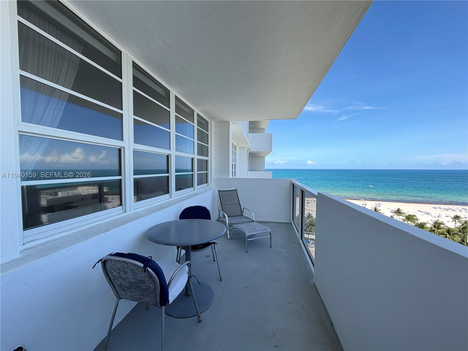A balcony with outdoor furniture overlooks the ocean and a sandy beach — 100 Lincoln Rd # 1230, Miami Beach FL 33139, MIAMI BEACH, FL