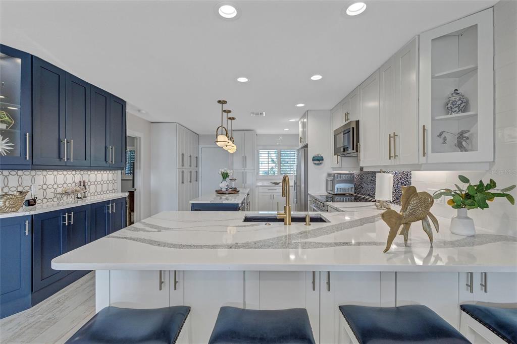 A kitchen features a white quartz island, navy blue cabinets, and white upper cabinetry — 7125 GULF OF MEXICO DRIVE UNIT 22, LONGBOAT KEY, FL