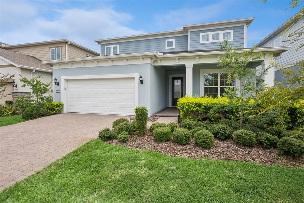 A two-story house with a blue exterior, a paved driveway, and a front porch — 13871 DESTIN BEACH LANE, ORLANDO, FL