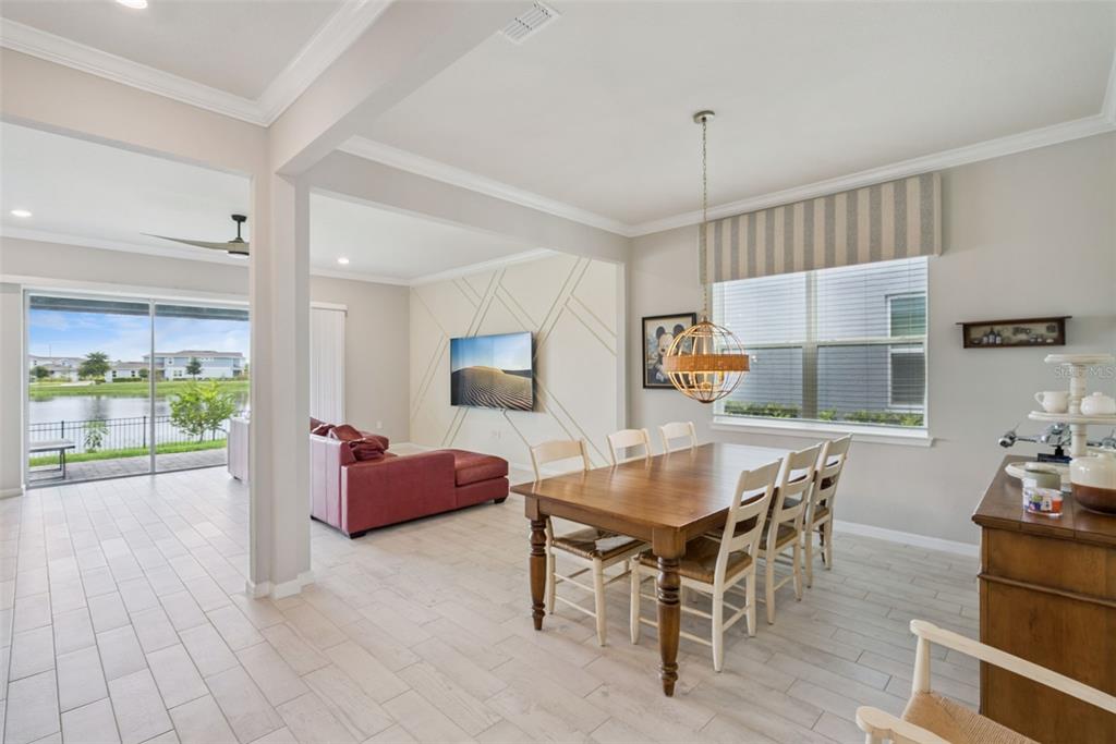 A dining area with a wooden table and chairs sits adjacent to a living room — 13871 DESTIN BEACH LANE, ORLANDO, FL