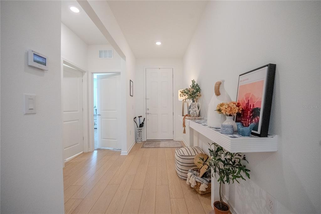 A bright entryway features light wood flooring, a white console shelf, and a front door — 8480 SW 52ND LANE ROAD, OCALA, FL