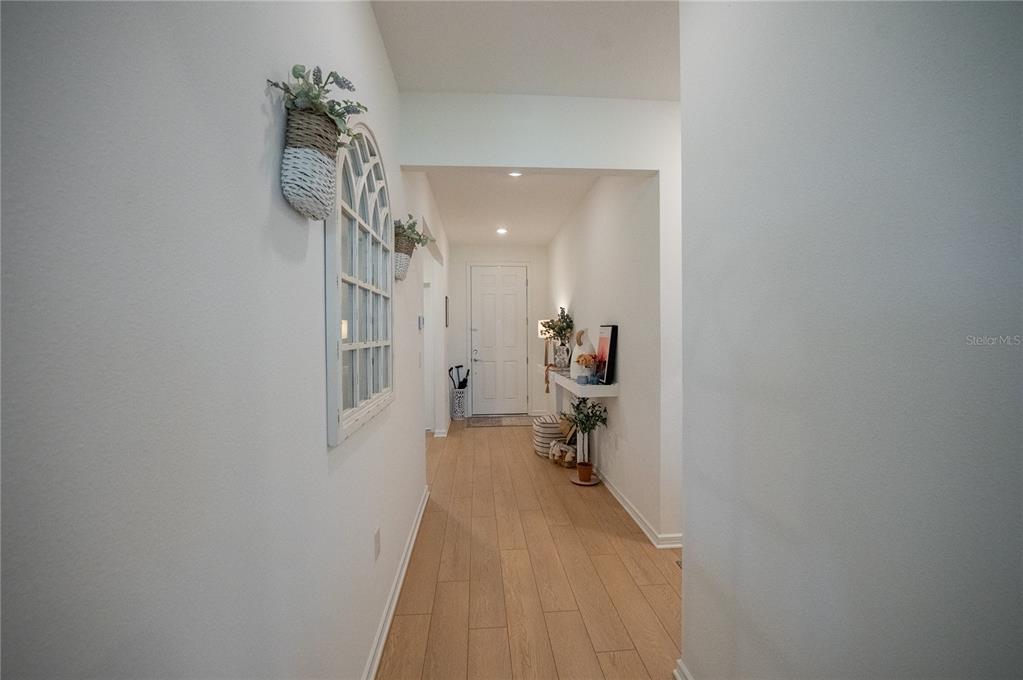 A bright hallway features light wood-look flooring, white walls, and a decorative arched wall mirror — 8480 SW 52ND LANE ROAD, OCALA, FL