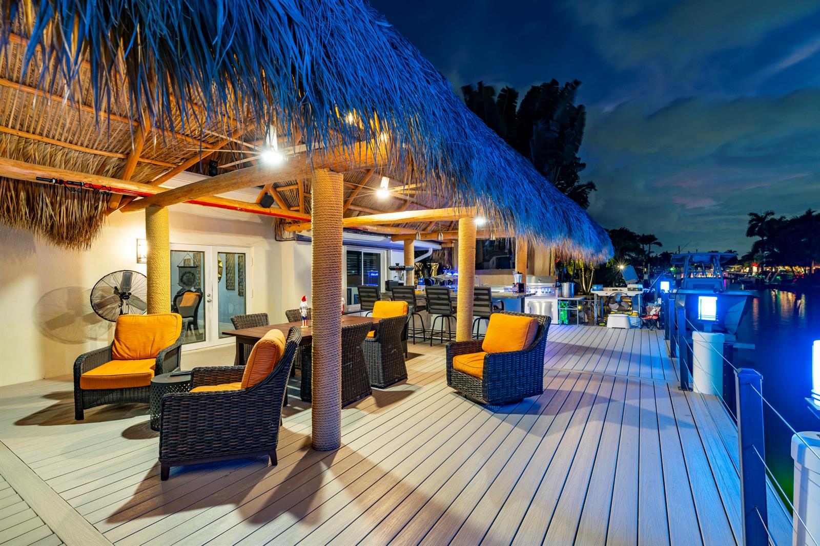 A covered outdoor deck with a tiki roof, dining set, and lounge chairs overlooking water — 851 SE 5th Avenue, Pompano Beach FL 33060, POMPANO BEACH, FL