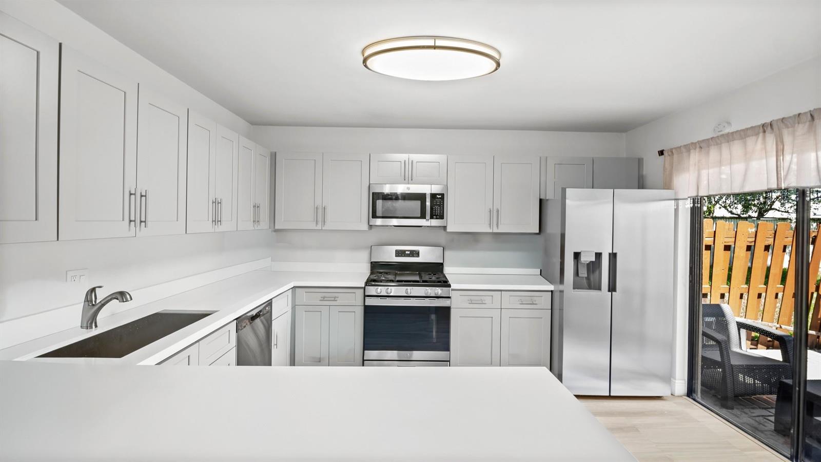A kitchen with light gray cabinets, stainless steel appliances, and a sliding glass door — 6363 Seven Springs Boulevard # A, FL 33463, FL