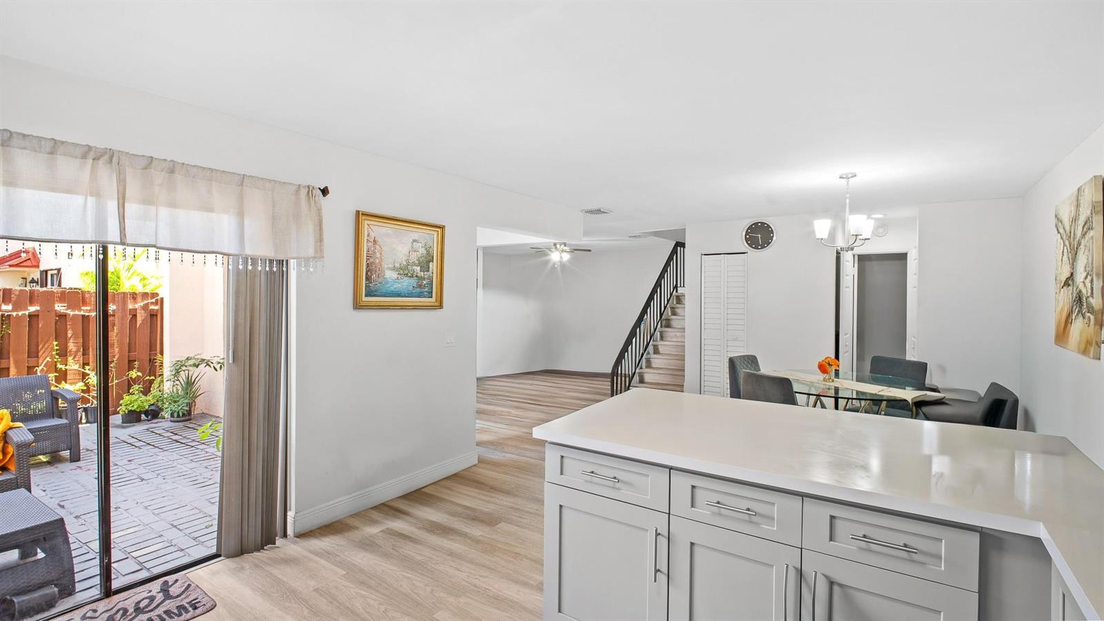 A kitchen island overlooks a dining area, a staircase, and a sliding door to a patio — 6363 Seven Springs Boulevard # A, FL 33463, FL