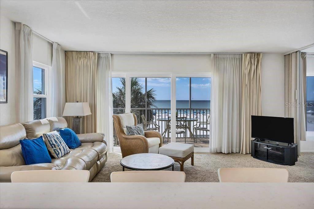 A living room features a leather sofa, wicker armchair, and sliding doors opening to a balcony — 6154 MIDNIGHT PASS ROAD UNIT 301, SARASOTA, FL