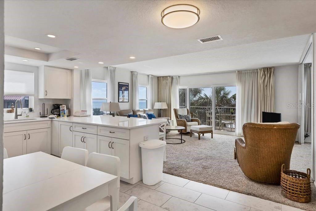An open-concept kitchen and living area features white cabinetry, tile flooring, and a balcony view — 6154 MIDNIGHT PASS ROAD UNIT 301, SARASOTA, FL