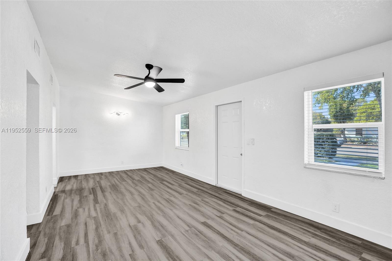 A bright, empty room features white walls, gray wood-look flooring, and a ceiling fan — 1582 NW 5th Ave, Pompano Beach FL 33060, POMPANO BEACH, FL