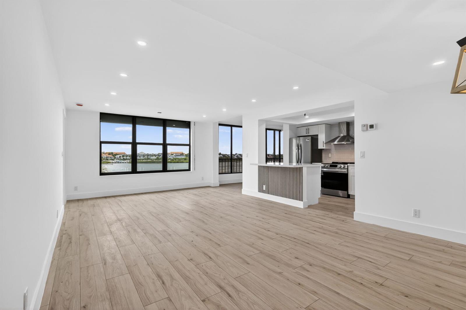 An open-concept living room with light wood flooring, recessed lighting, and a view of water — 1748 Jupiter Cove Drive # 319, Jupiter FL 33469, JUPITER, FL
